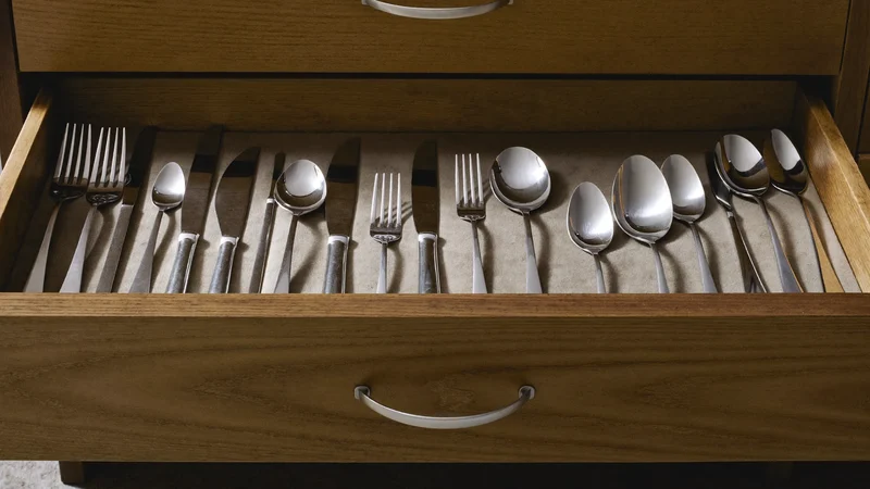Besteck geordnet in einer offenen Holzschublade mit Stoffeinlage, Illustration